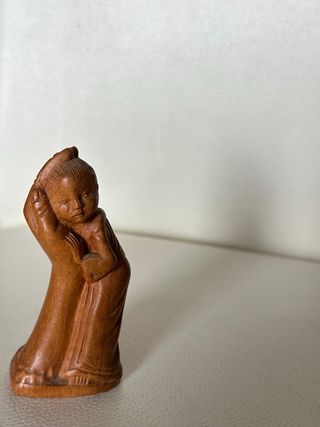 Piccola scultura in legno di un bambino che riposa