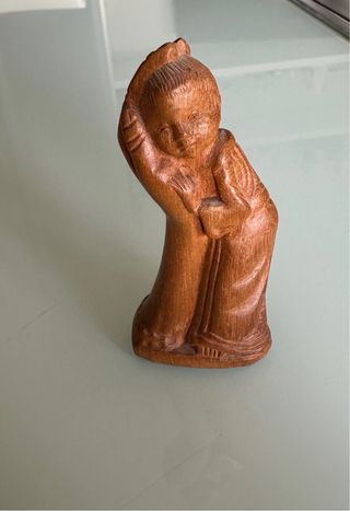 Piccola scultura in legno di un bambino che riposa