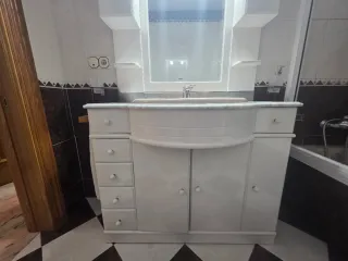 Mueble de baño con lavabo de mármol y espejo.
