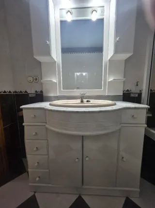 Mueble de baño con lavabo de mármol y espejo.