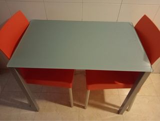 Mesa de cristal con 2 sillas naranjas