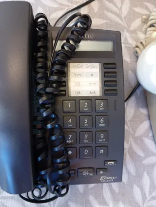 Teléfono antiguo beige y uno negro Alcatel.