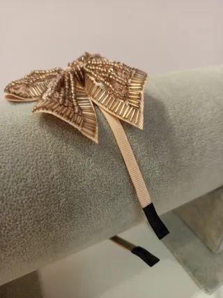 Diadema con lazo de abalorios color rosa claro.