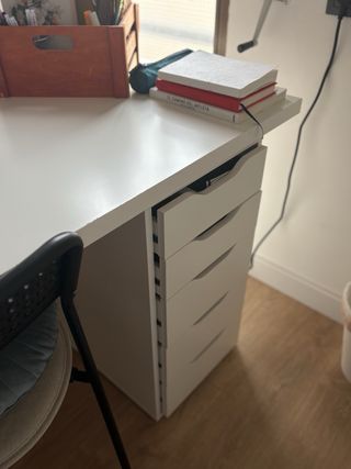 Mesa IKEA blanca con cajoneras y patas.