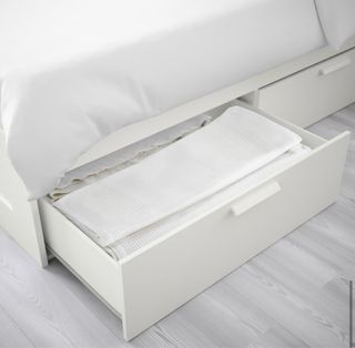 Cama blanca con cajones de madera