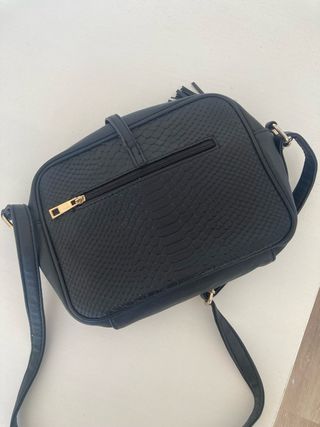 Bolso negro con flecos y detalle dorado