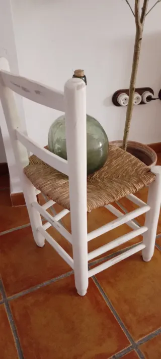 Damajuana verde, silla y sombrero paja.