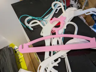 Perchas infantiles de plástico blancas y rosa.