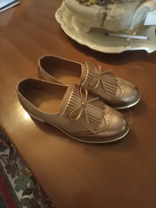 Zapatos dorados con flecos y lazo