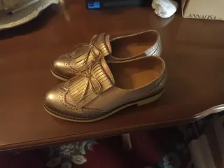 Zapatos dorados con flecos y lazo