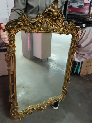 Espejo antiguo dorado con marco tallado.
