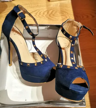 Zapatos de tacón azul con tachas doradas.