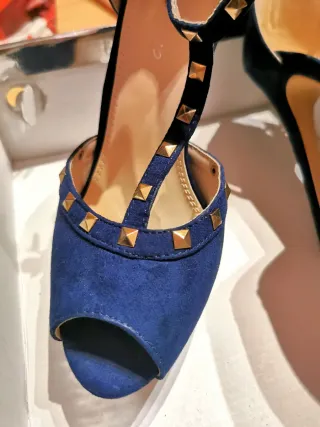 Zapatos de tacón azul con tachas doradas.