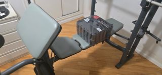 Banco de pesas con discos y barras.