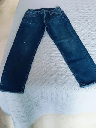 Vaqueros azules con detalle de manchas blancas.
