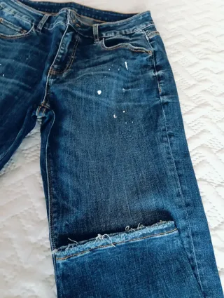 Vaqueros azules con detalle de manchas blancas.