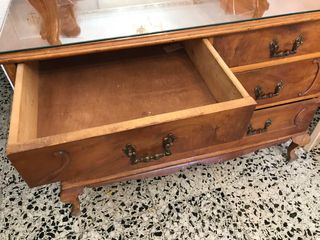 Cómoda antigua de madera con tapa de cristal.
