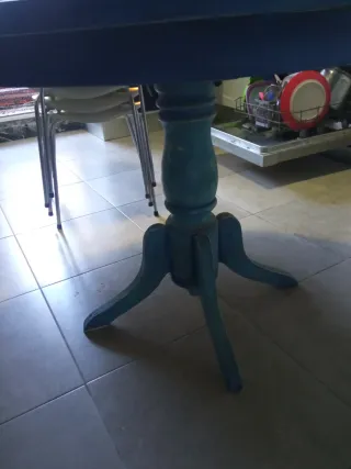 Mesa redonda azul y cuatro sillas.