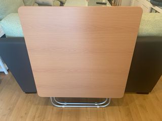 Mesa plegable con acabado en madera y metal.
