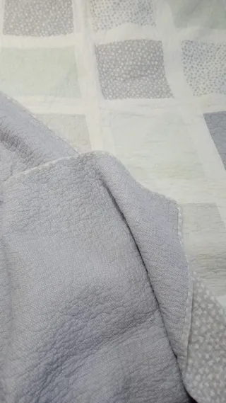 Colcha de tela gris y blanca