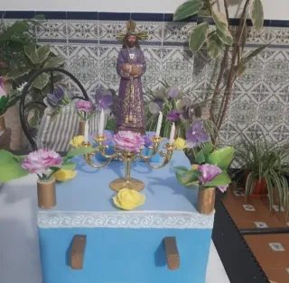 Figura religiosa con candelabro y flores