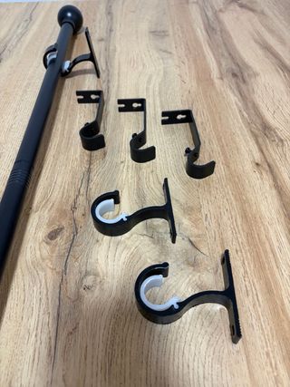 Barra de cortina negra con soportes.