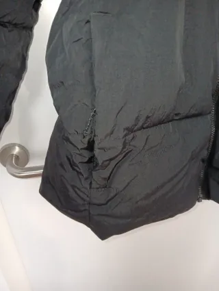 Plumas Columbia Negro tiene un defecto en la manga