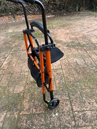 Andador naranja con asiento y cesta