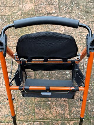 Andador naranja con asiento y cesta