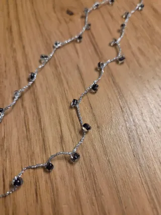Collana con filo argentato e perline nere.