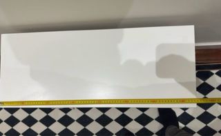 Una mesita / cómoda blanca con cestas de mimbre.