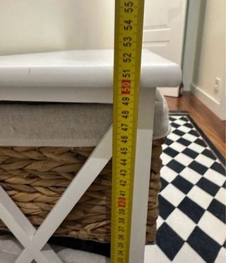 Una mesita / cómoda blanca con cestas de mimbre.