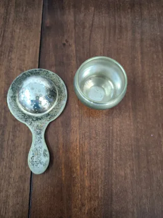 Filtro/colador de té antiguo con vaso recolector.