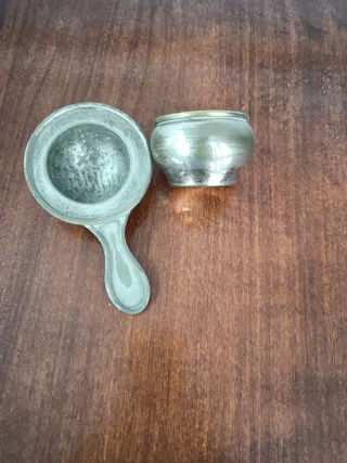 Filtro/colador de té antiguo con vaso recolector.