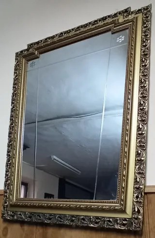 Espejo antiguo dorado con marco tallado.