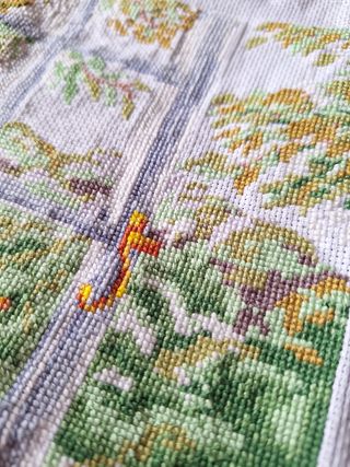 Bordado a mano de un gato mirando por la ventana