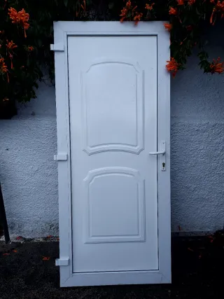 Puerta blanca exterior con marco, bombin y llabe.