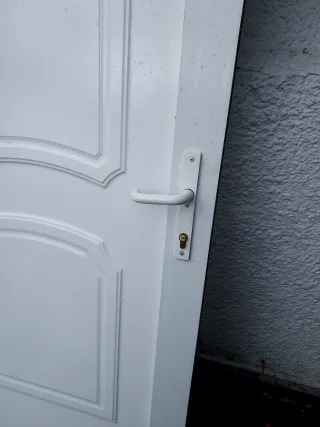 Puerta blanca exterior con marco, bombin y llabe.