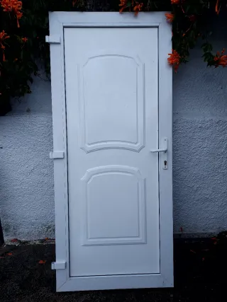 Puerta blanca exterior con marco, bombin y llabe.