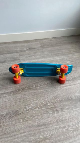 Monopatín azul 55cm con ruedas naranjas