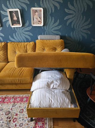 Sofá cama de terciopelo mostaza.