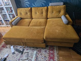 Sofá cama de terciopelo mostaza.