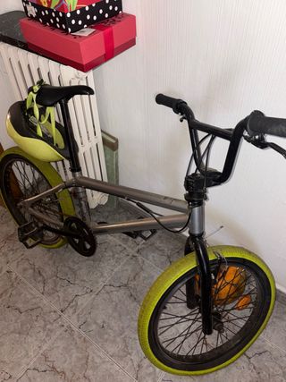 BMX plateada con ruedas verdes fluorescentes.