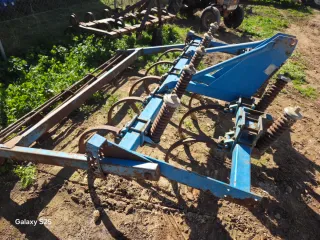 Cultivador agrícola azul con muelles