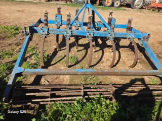 Cultivador agrícola azul con muelles