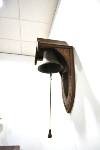 Antigua campana de pared con soporte de madera