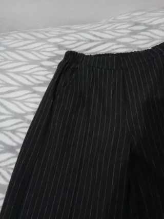 Pantalones gris oscuro de rayas. Con bolsillos.