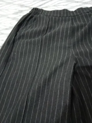 Pantalones gris oscuro de rayas. Con bolsillos.