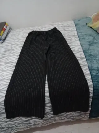 Pantalones gris oscuro de rayas. Con bolsillos.