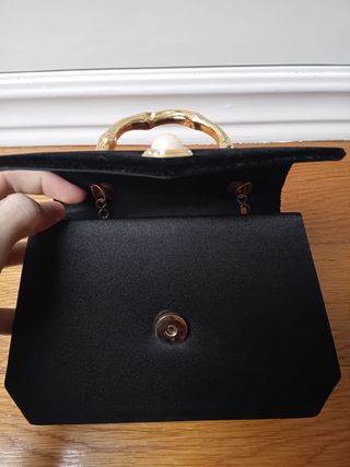 Bolso de mano negro con asa dorada